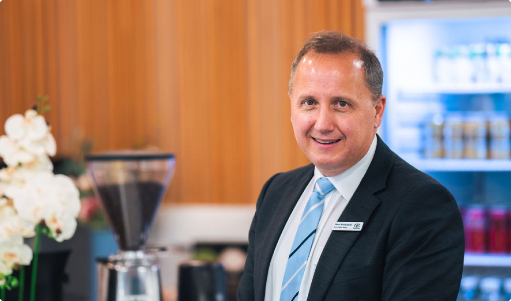 Meon Nehrybecki, Principal Dealer at Terry Shields Toyota in Parramatta, in a suit and tie, smiling at the camera.